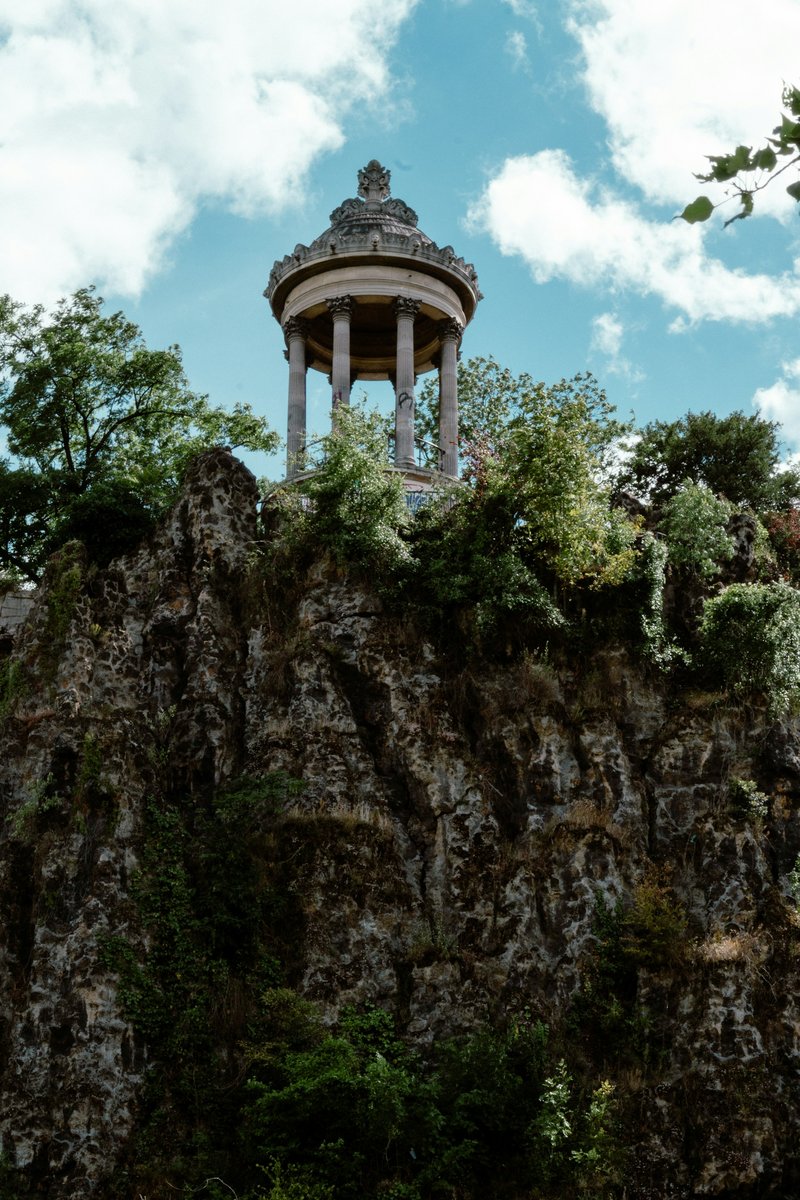 Le temple de la Sibylle au sommet d'un rocher couvert de végétation, sous un ciel bleu