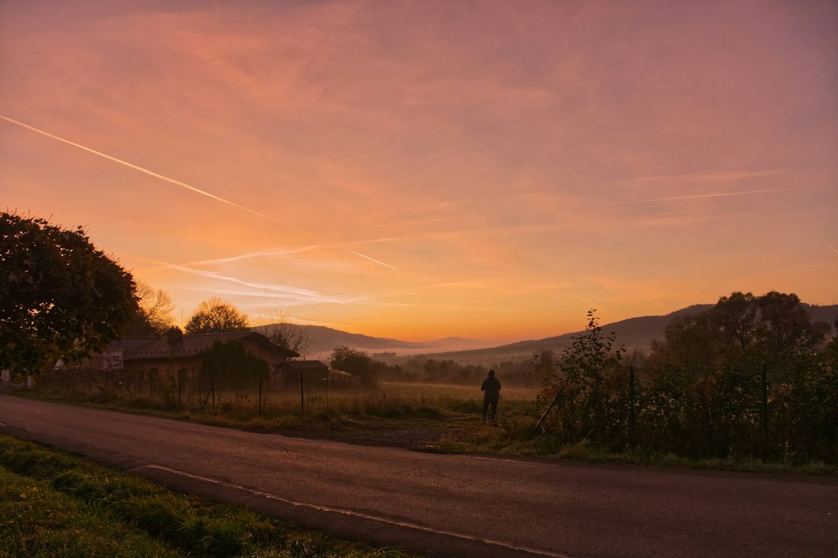 Coureur de dos sur un chemin de gravier sous un très grand ciel nuageux