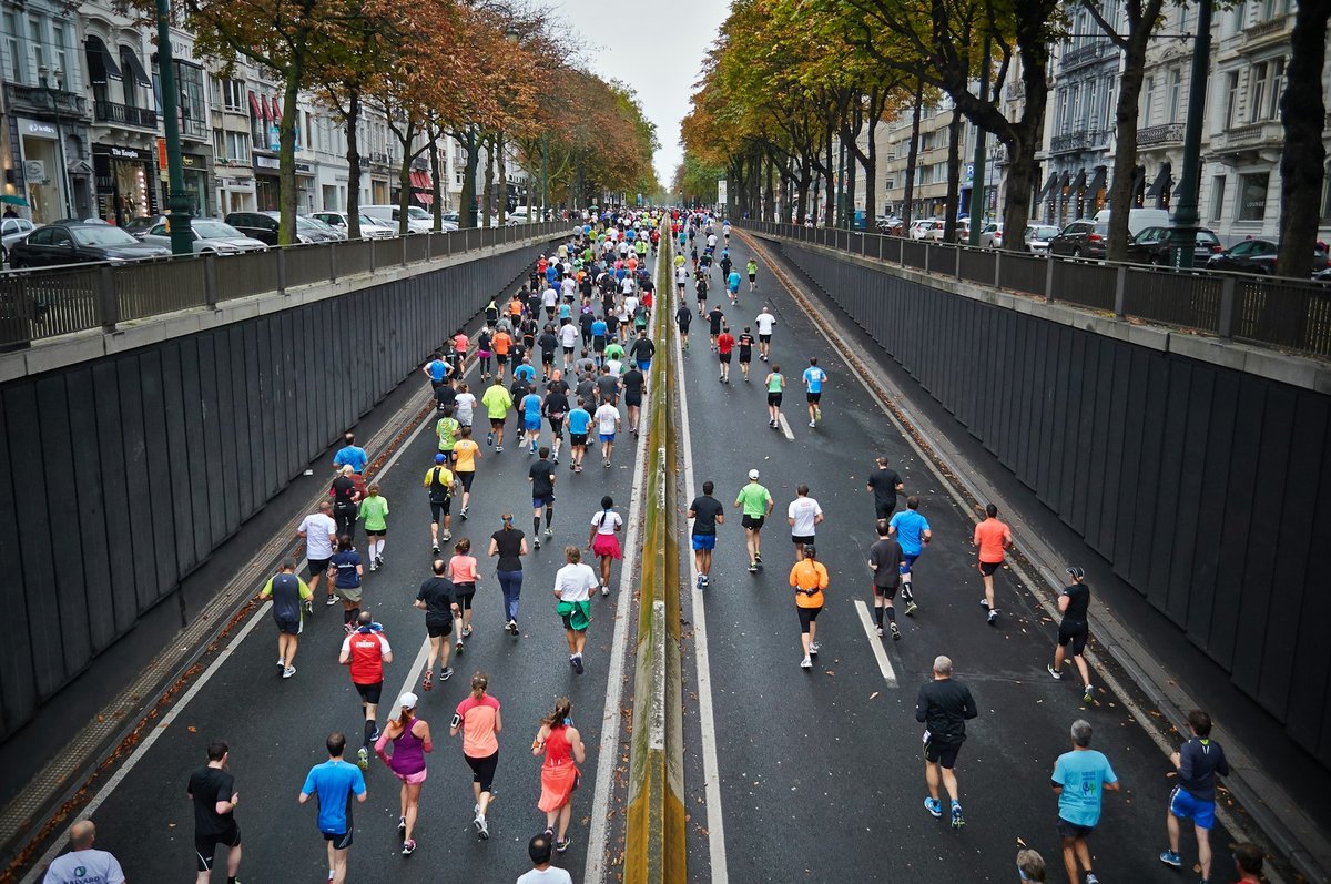 Des centaines de coureurs vus de haut dans une avenue bordée d'arbres, pendant un marathon
