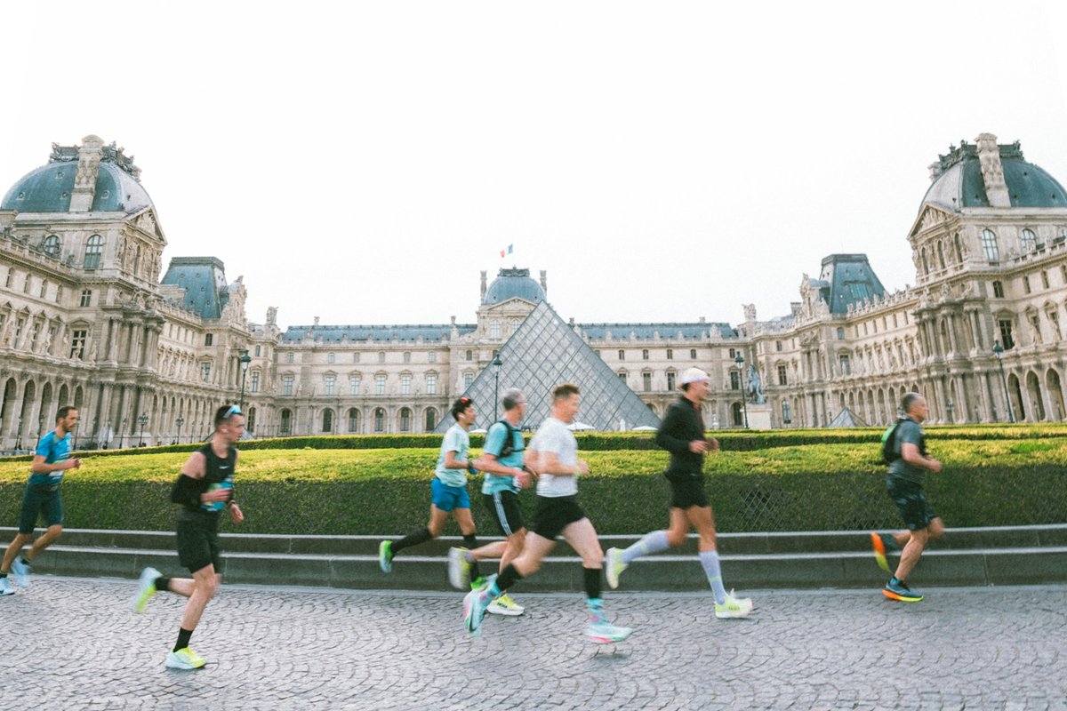 Coureurs d'une course sur route qui passent devant le Louvre et sa pyramide de verre