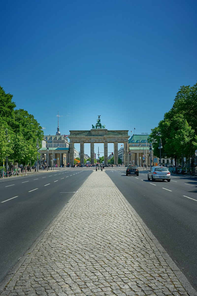 Avenue rectiligne qui mène à la porte de Brandebourg sous un ciel bleu