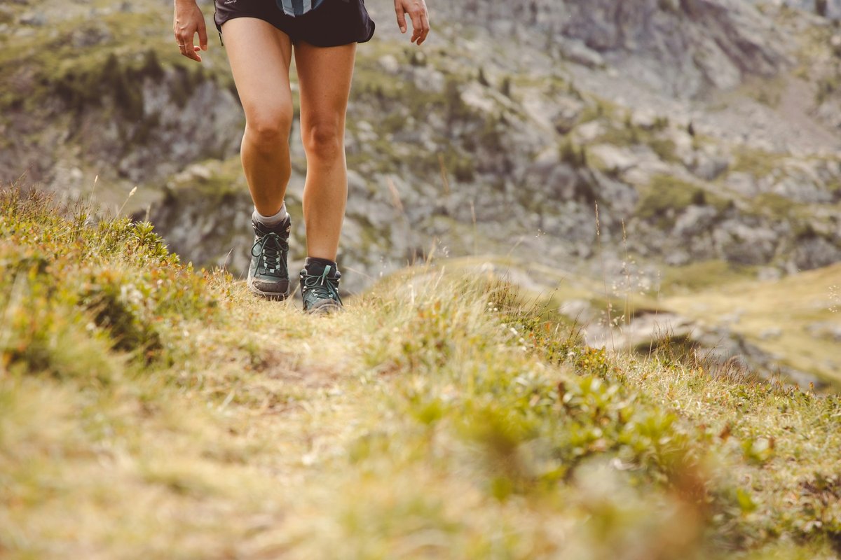Jambes d'une coureuse sur un sentier herbeux et étroit, en pleine foulée